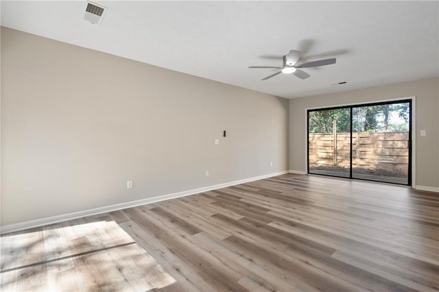 spare room featuring a ceiling fan, visible vents, baseboards, and wood finished floors