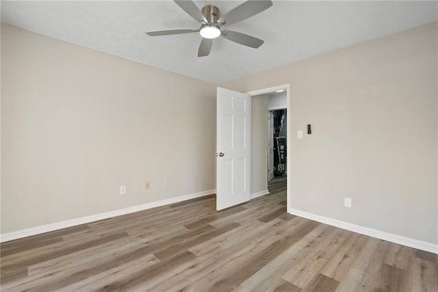 empty room featuring wood finished floors, a ceiling fan, and baseboards