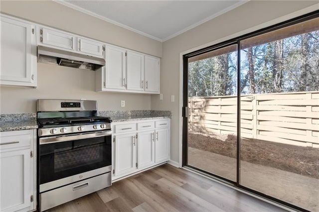 kitchen with ornamental molding, white cabinetry, wood finished floors, under cabinet range hood, and stainless steel gas range oven