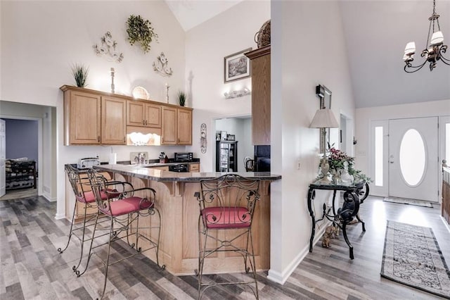 144 Bobs Dr SW, Mableton, GA 30126 - kitchen featuring high vaulted ceiling, light wood-style flooring, hanging light fixtures, a kitchen bar, and a notable chandelier