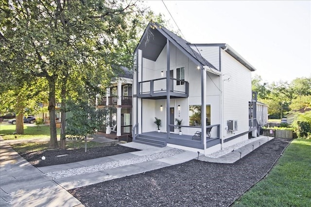 view of property exterior featuring a balcony, covered porch, and a yard