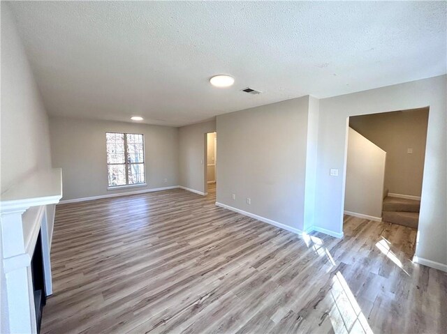 unfurnished living room featuring light hardwood / wood-style flooring and a textured ceiling