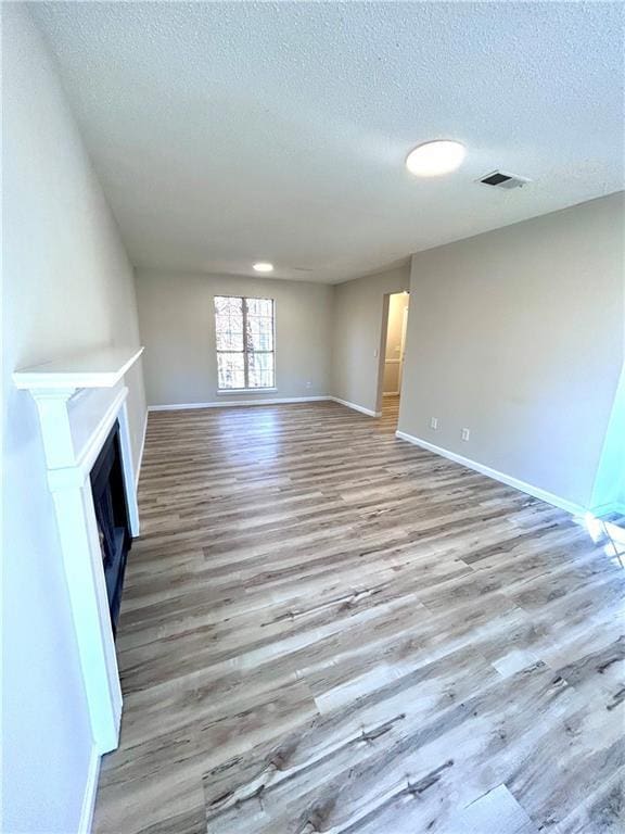 unfurnished living room featuring a textured ceiling and light wood-type flooring