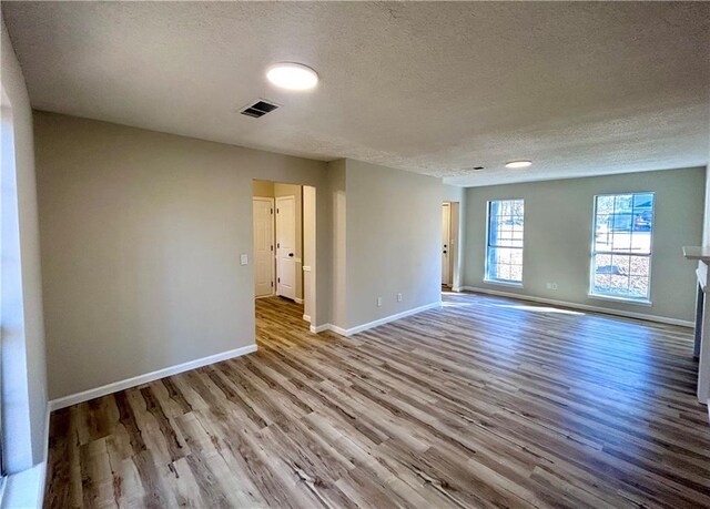 unfurnished room with a textured ceiling and light hardwood / wood-style floors