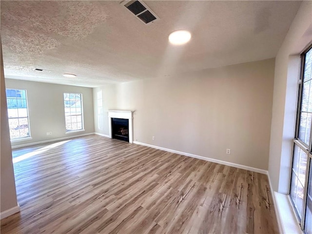 unfurnished living room with a textured ceiling and light hardwood / wood-style flooring