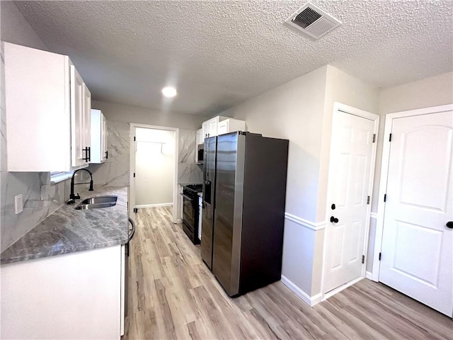 kitchen featuring white cabinets, light wood-type flooring, stainless steel appliances, and sink