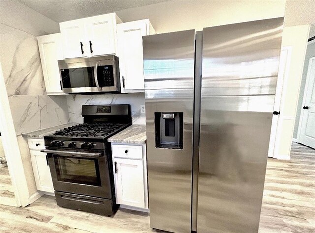 kitchen featuring white cabinets, light hardwood / wood-style floors, and appliances with stainless steel finishes