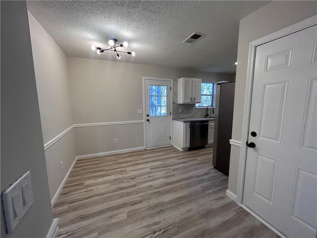 interior space featuring backsplash, light hardwood / wood-style flooring, dishwasher, white cabinets, and stainless steel refrigerator