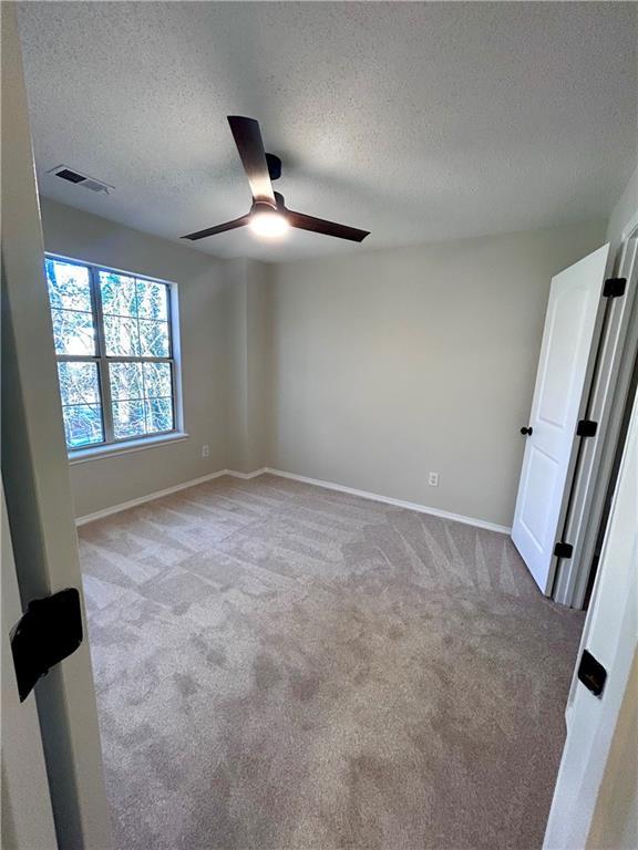 spare room with light carpet, a textured ceiling, and ceiling fan