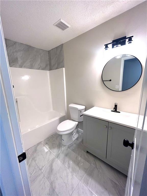 full bathroom featuring vanity, tub / shower combination, toilet, and a textured ceiling