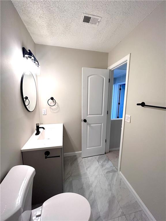 bathroom with vanity, a textured ceiling, and toilet