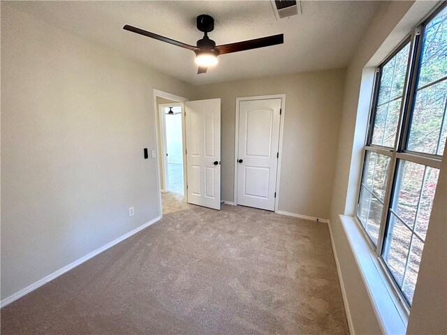 unfurnished bedroom with ceiling fan and light colored carpet