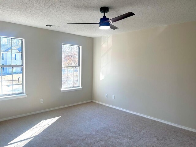 carpeted spare room with ceiling fan and a textured ceiling