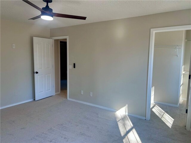 unfurnished bedroom featuring a textured ceiling, a closet, ceiling fan, and light colored carpet