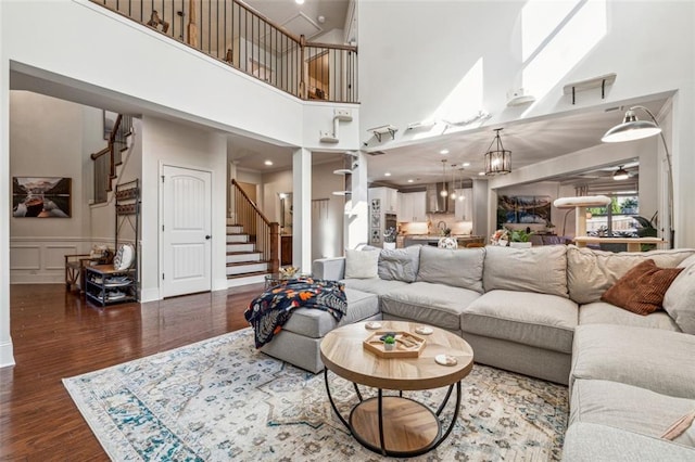 living room with a chandelier, dark hardwood / wood-style floors, a towering ceiling, and a skylight