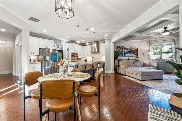 dining area with beamed ceiling, dark wood-type flooring, crown molding, and ceiling fan with notable chandelier