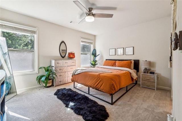 bedroom with light carpet, multiple windows, and ceiling fan