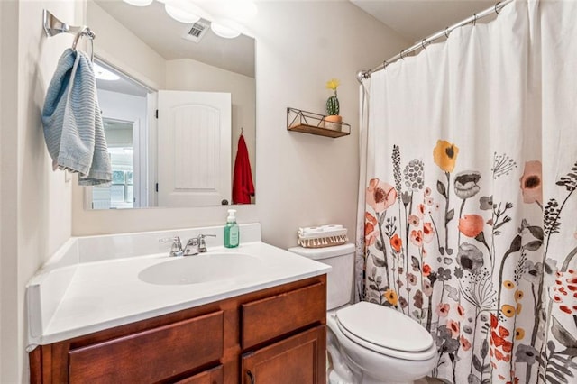 bathroom featuring vanity, walk in shower, and toilet