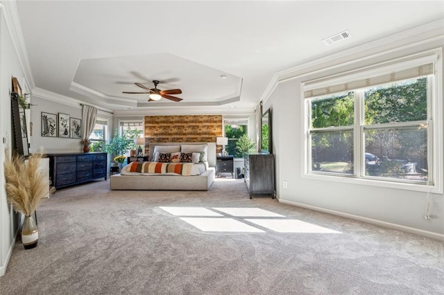 unfurnished bedroom with carpet, multiple windows, a tray ceiling, and ceiling fan