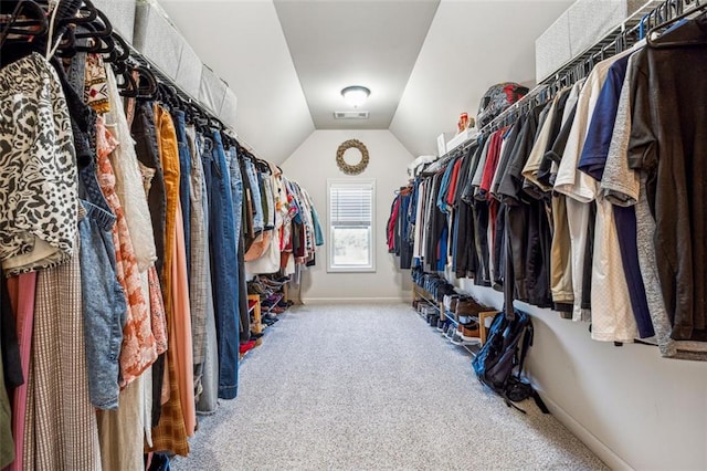 walk in closet with vaulted ceiling and light colored carpet