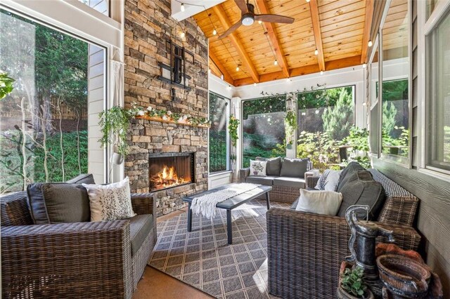 sunroom / solarium featuring ceiling fan, an outdoor stone fireplace, wooden ceiling, and vaulted ceiling with beams