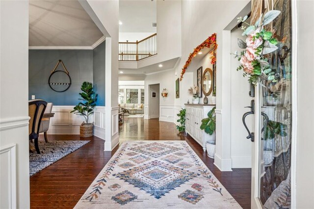 foyer with ornamental molding, dark hardwood / wood-style flooring, and a high ceiling