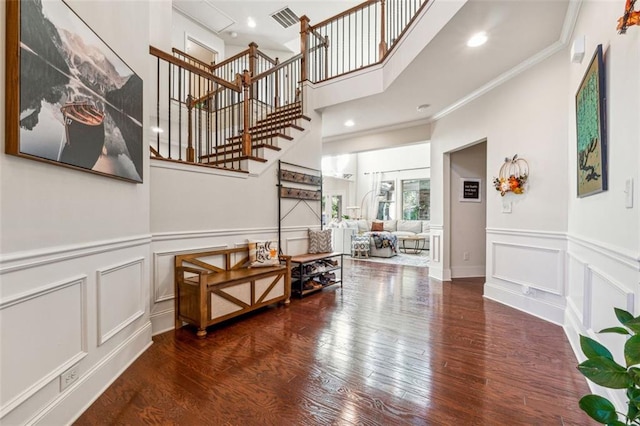 entryway with ornamental molding and dark hardwood / wood-style floors