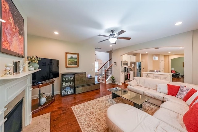 living area with a premium fireplace, stairway, wood finished floors, and recessed lighting