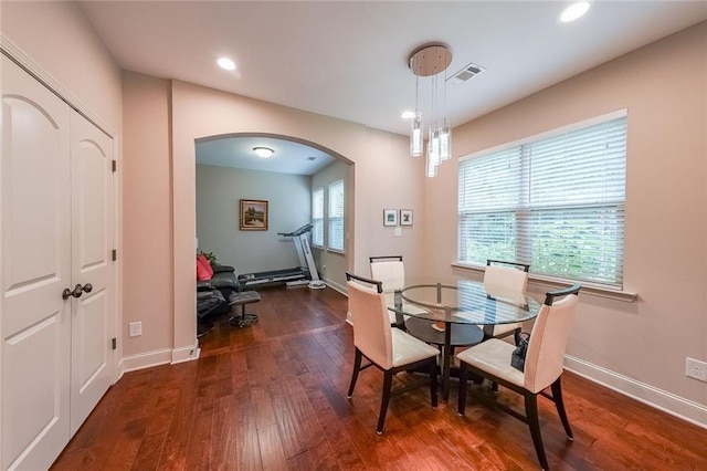 dining space with arched walkways, dark wood-style flooring, recessed lighting, visible vents, and baseboards