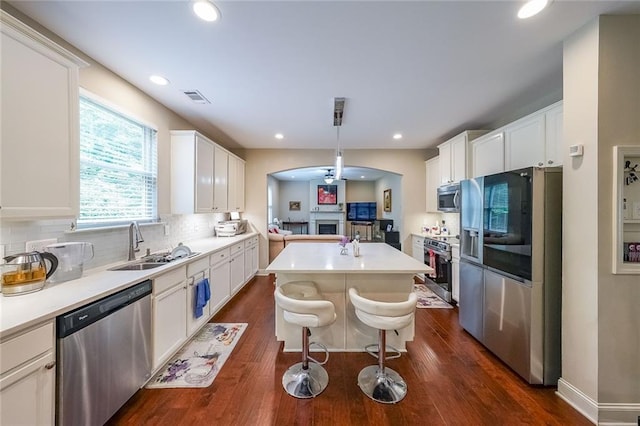 kitchen with visible vents, a ceiling fan, appliances with stainless steel finishes, a center island, and a sink