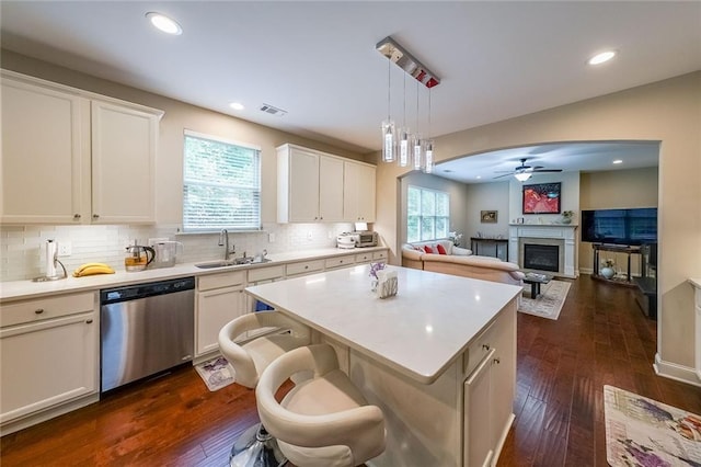 kitchen with a center island, a fireplace, light countertops, stainless steel dishwasher, and a sink