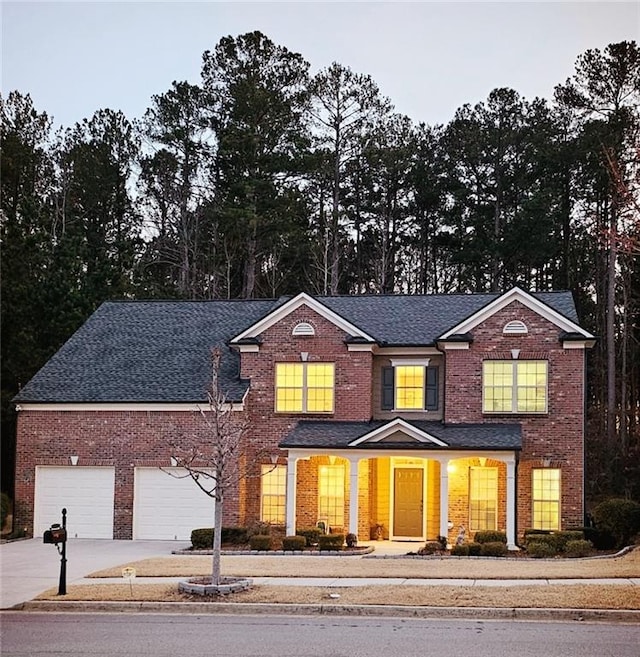 view of front of home featuring a shingled roof, brick siding, driveway, and a garage