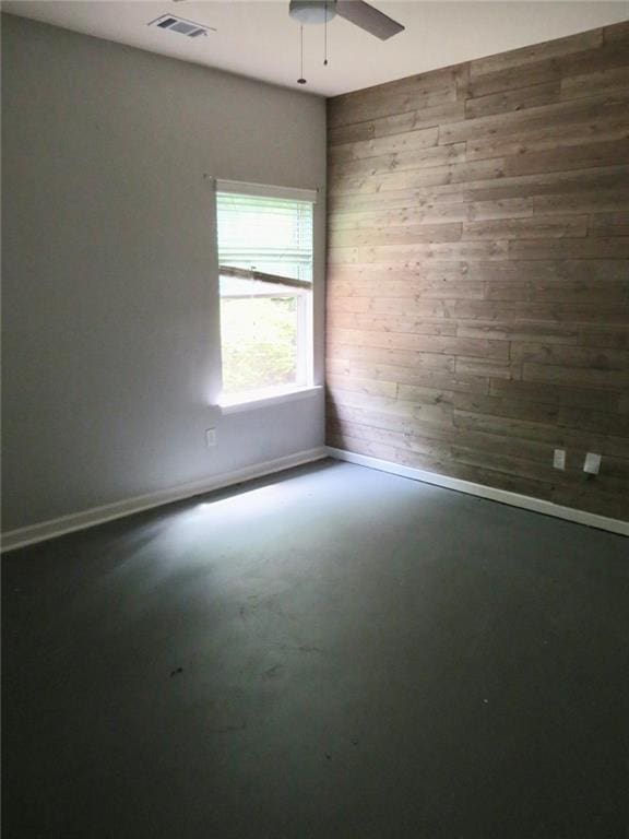 58 Torero Trl, Newnan, GA 30263 - empty room with wooden walls, ceiling fan, baseboards, and concrete flooring