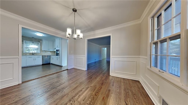 unfurnished dining area featuring ornamental molding, dark hardwood / wood-style floors, a chandelier, and sink