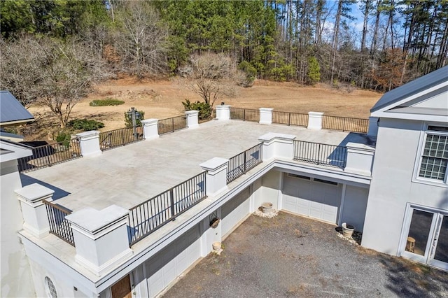 view of patio / terrace with a balcony, driveway, a garage, and fence