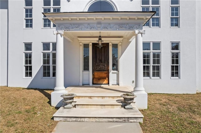 entrance to property with a yard and stucco siding