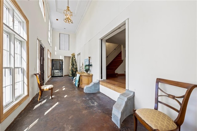 interior space featuring a towering ceiling, an inviting chandelier, concrete floors, and stairway