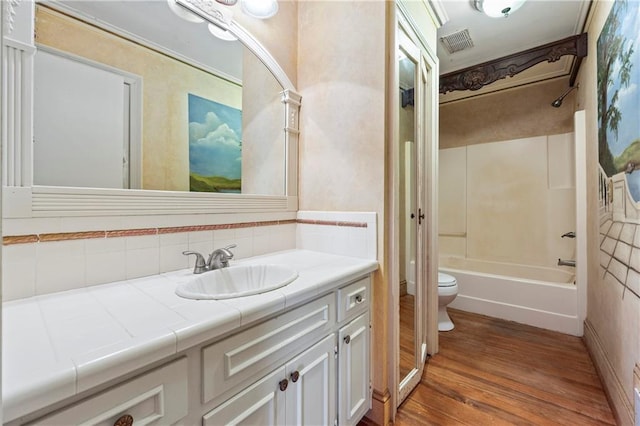 full bath with visible vents, toilet, vanity, shower / tub combination, and wood finished floors