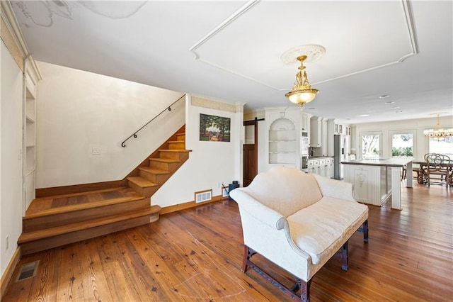 living area with stairway, a barn door, visible vents, and dark wood finished floors