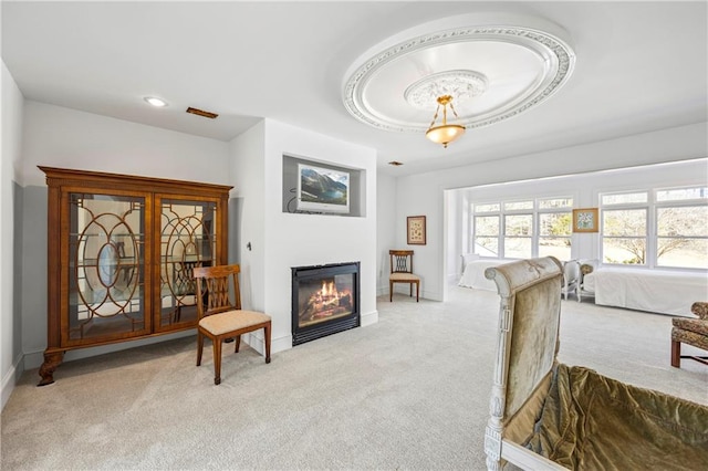 living room featuring carpet, a tray ceiling, baseboards, and a glass covered fireplace