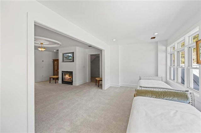 bedroom featuring light carpet, recessed lighting, baseboards, and a glass covered fireplace