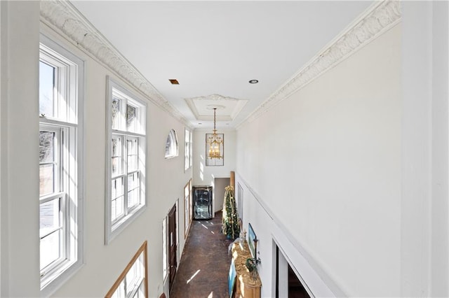 hallway featuring a notable chandelier, a tray ceiling, and crown molding