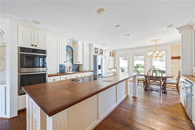 kitchen with stainless steel appliances, butcher block counters, dark wood-style flooring, and a sink