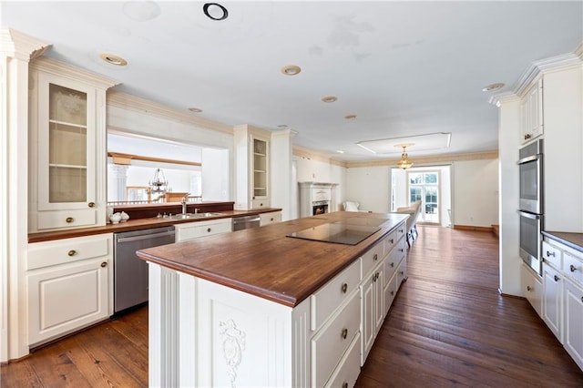 kitchen with a kitchen island, glass insert cabinets, stainless steel appliances, wooden counters, and a sink