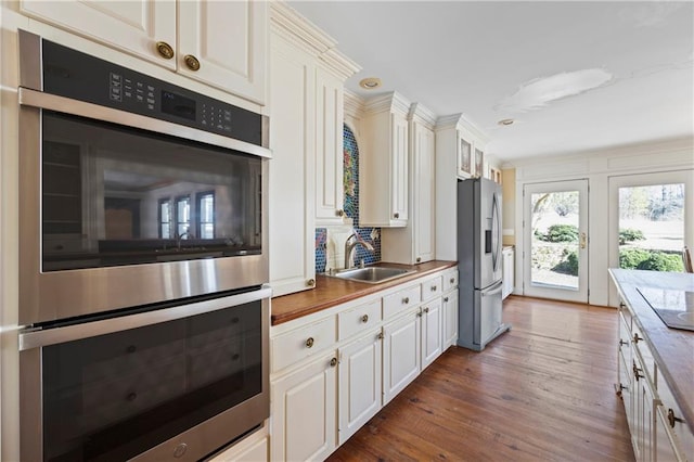 kitchen with dark wood-type flooring, a sink, white cabinets, light countertops, and appliances with stainless steel finishes