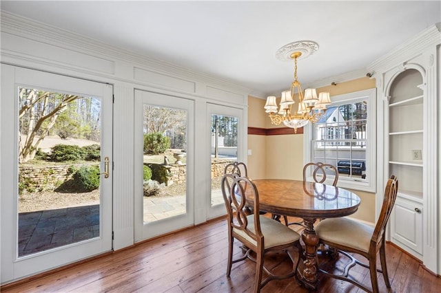 dining space featuring an inviting chandelier, ornamental molding, and hardwood / wood-style floors