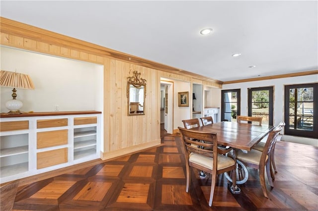 dining area with wooden walls, ornamental molding, and recessed lighting