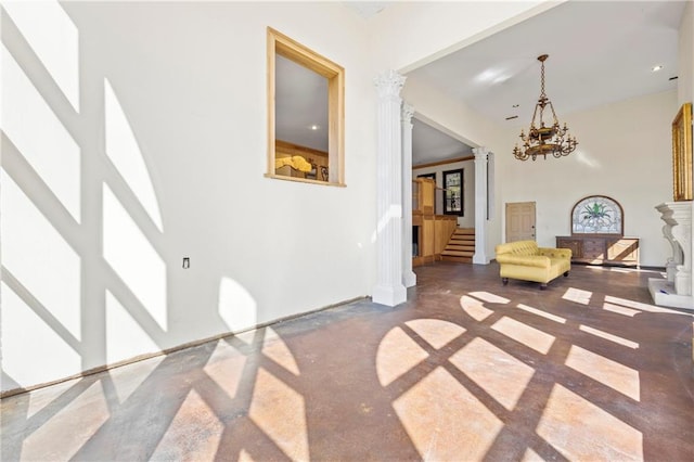 living area with decorative columns, a high ceiling, stairs, finished concrete floors, and a notable chandelier