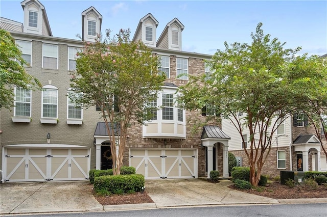 multi unit property featuring concrete driveway, brick siding, and an attached garage