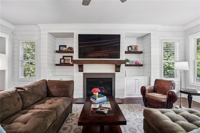 living room with a large fireplace, plenty of natural light, ornamental molding, and wood finished floors